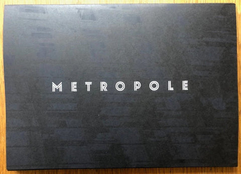 The photography book cover of Metropole by Lewis Bush. Paperback black with white title.