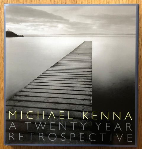 The photography book cover of Michael Kenna: A Twenty Year Retrospective by Michael Kenna. Hardback with b&w cover image of a dock. Signed.