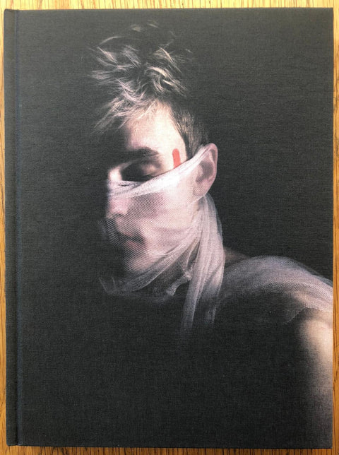 The photography book cover of Rite by Michael Sondergaard. Hardback image of someone with a scarf wrapped around their mouth. Signed.