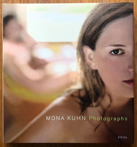 The photography book cover of Photographs by Mona Kuhn. Hardback cover with image of a woman looking into the camera.
