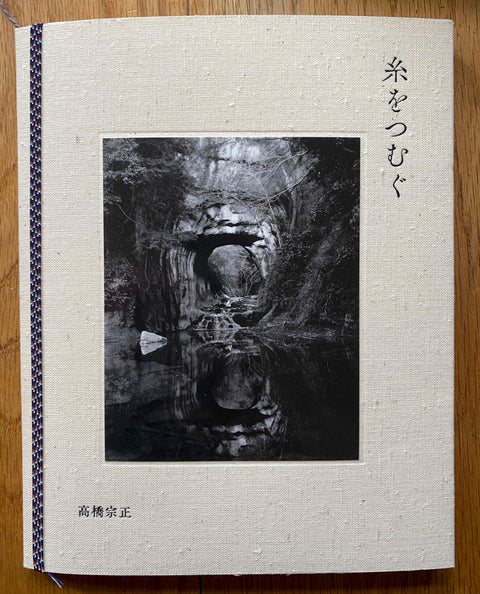 The photography book cover of Spinning a Yarn by Munemasa Takahashi. Paperback with B&W image of a natural bridge above water. Signed.