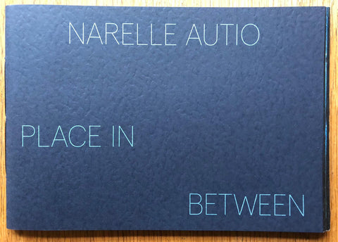 The photography book cover of Place in Between by Narelle Autio. Paperback in navy blue.