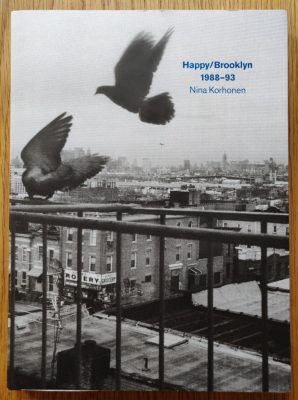 The photography book cover of Happy / Brooklyn 1988 - 93 by Nina Korhonen. Paperback in B&W with blue title.