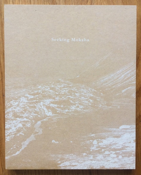 The photography book cover of Seeking Moksha by Nishant Shukla. Hardback beige cover with mountains.