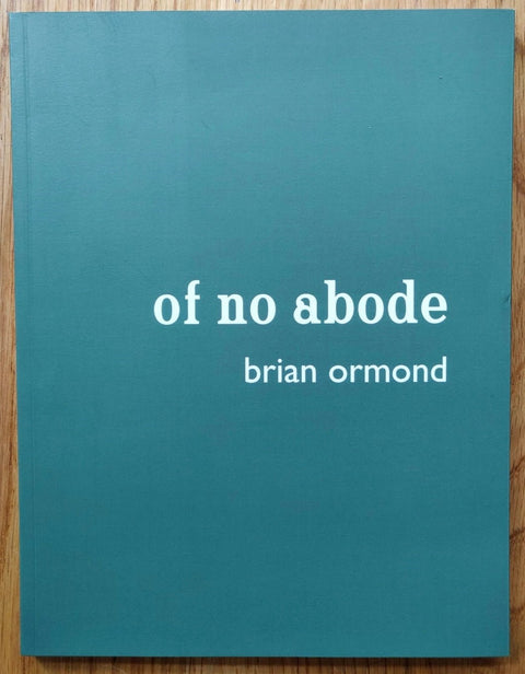 The photography book cover Of No Abode by Brian Ormond. Paperback in blue with white text.