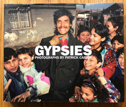 The photography book cover of Gypsies by Patrick Cariou. Hardback with image of lots of children surrounding a man.