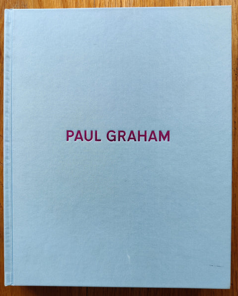 The photography book cover of Paul Graham: Photographs 1981-2006 by Paul Graham. Hardback in white with red title.