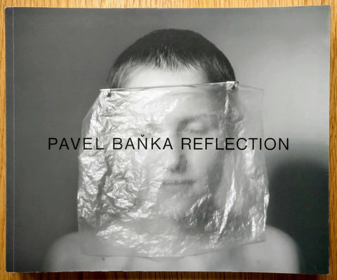 The photography book cover of Reflection by Pavel Banka. Hardback B&W photograph of a boy on the cover.