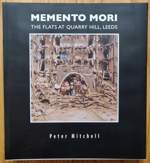 The photography book cover of Memento Mori The Flats at Quarry Hill, Leeds by Peter Mitchell. Paperback in black with centred photograph of a demolition site.