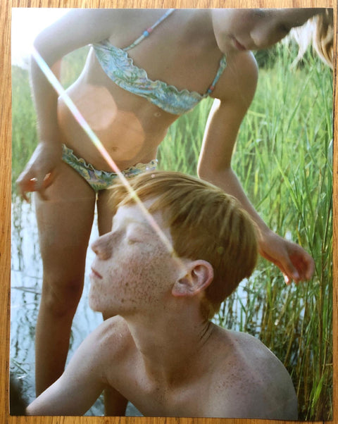 The photography book cover of Kamasz Nyar by Petra Collins. Hardback with image of two children by a pond. Signed.