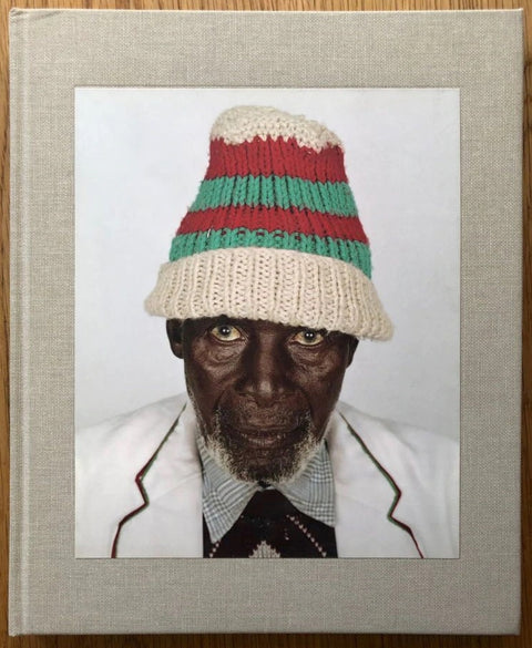 The photography book cover of Looking Aside by Pieter Hugo. Hardback with cover image of a man in a hat looking into the camera.