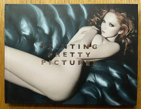 The photography book cover of Painting Pretty Pictures by Rankin. Hardback with nude image of a woman with red hair lying on a leather sofa.