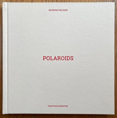 The photography book cover of Polaroids 2007 - 2008 by Raymond Molinar. Hardback in white with red writing. Signed.