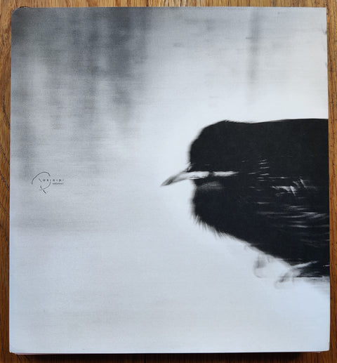 The photography book cover of Panopticon by Riccardo Dogana. Ppaerback with blurred image of a black bird on the cover. Signed. Comes in sealed reflective bag.