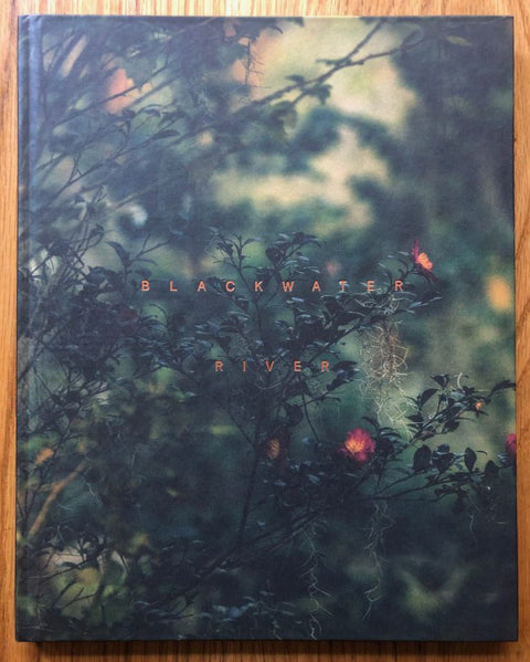 The photography book cover of Blackwater River by Robbie Lawrence. Hardback with close-up cover photo of a bush with little red/orange flowers on.