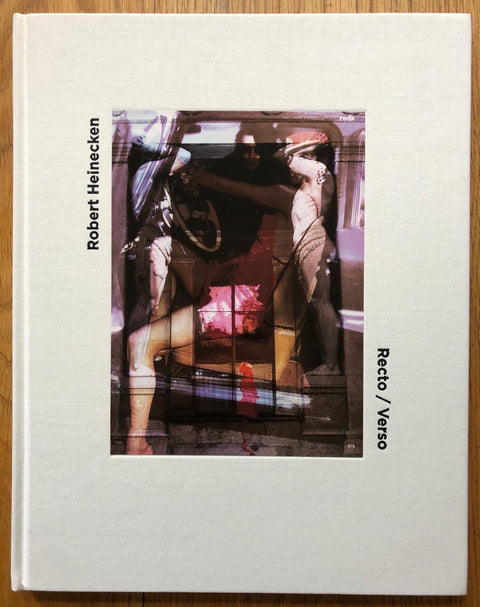 The photography book cover of Recto/Verso by Robert Heinecken. Hardback in white with image of a woman in a care overlayed on image of two statues.