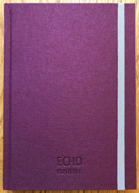 The photography book cover of Echo by Roberto Kusterle. Hardback in purple with grey elastic to close book. Signed.