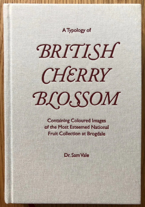The photography book cover of British Cherry Blossom by Sam Vale. Hardback in cream with red cherry coloured text.