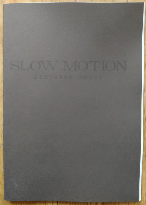 The photography book cover of Slow Motion (L’Atelier RisoGraphique) by Stephane Duroy. In softcover brown.