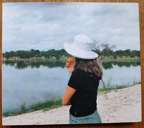 The photography book cover of How Beautiful This Place Can Be by Stuart O'Sullivan. Hardback with image of a girl in a white hat eating a peach.