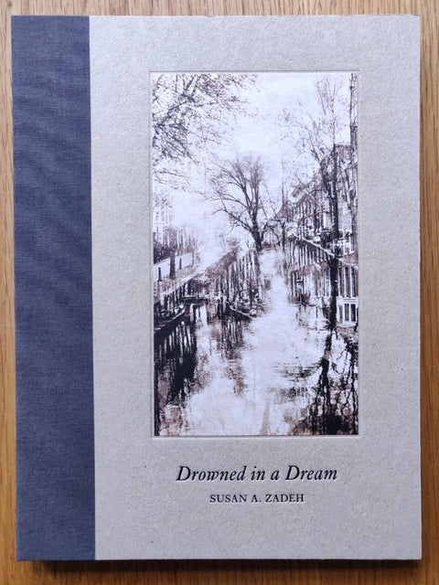 The photography book cover of Drowned in A Dream by Susan A Zadeh. Hardback with navy blue binding.