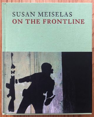 The photography book cover of On the Frontline by Susan Meiselas. Hardback in light turquoise with graffiti image of someone holding a gun on the cover.