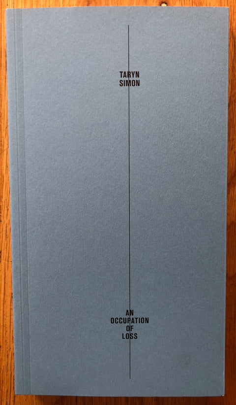 An Occupation of Loss by Taryn Simon. Paperback blue/grey cover with line down the middle of title and author.