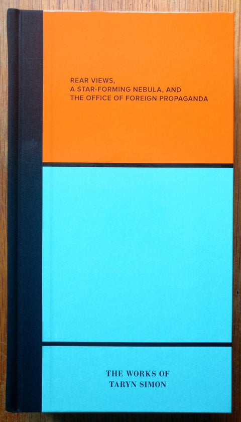 The photography book cover of Rear Views, A Star-Forming Nebula, and The Office of Foreign Propaganda by Taryn Simon. Hardback with bright blue and orange squares.