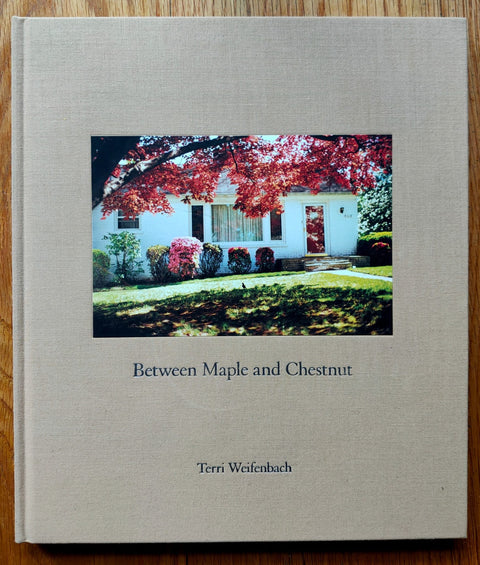The photography book cover of Between Maple and Chestnut by Terri Weifenbach. Hardback in beige with central photo of a house in the sun.