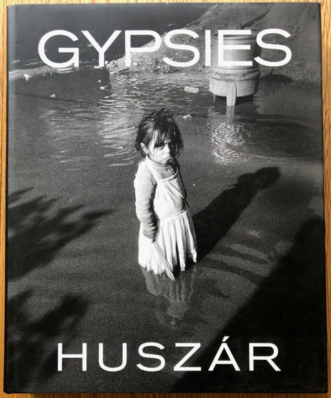 The photography book cover of Gypsies by Tibor Huszar. Hardback with B&W cover image of a little girl standing in water.