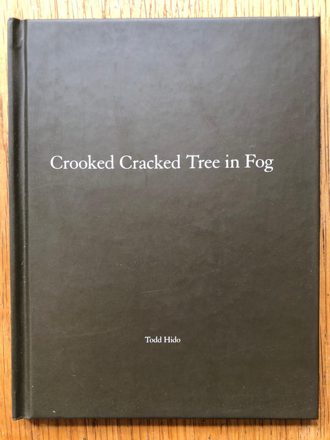 The photography book cover of Crooked Cracked Tree in Fog by Todd Hido. Hardback in grey/green. Signed.