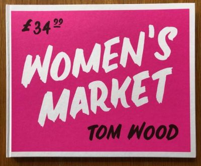 The photobook cover of Women's Market by Tom Wood. Hardback in pink with white writing.