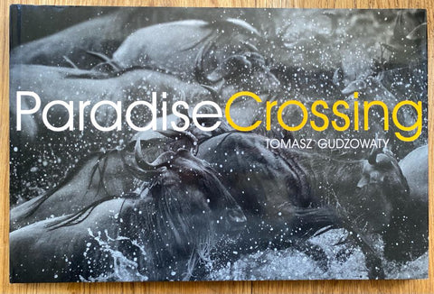 The photography book cover of Paradise Crossing by Tomasz Gudzowaty. Hardback in B&W with yellow "Crossing".