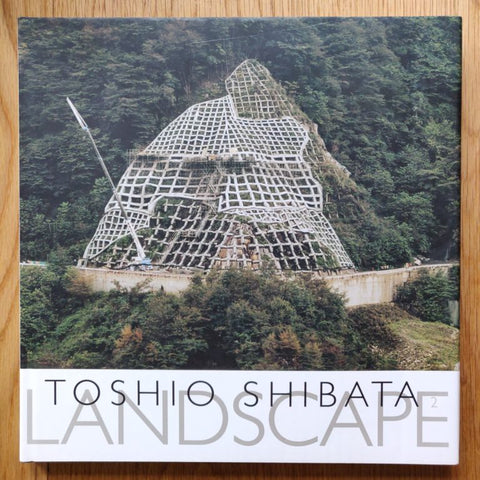 The photography book cover of Landscape 2 by Toshio Shibata. Hardback with image of a large netted structure on a hill.