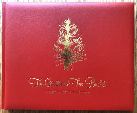 The photography book cover of The Christmas Tree Bucket by Trent Parke. Hardback in leather red with gold christmas tree and title.