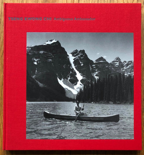 The photography book cover of Ambiguous Ambassador by Tseng Kwong Chi. Hardback in bright red with image of someone in a kayak on a lake.
