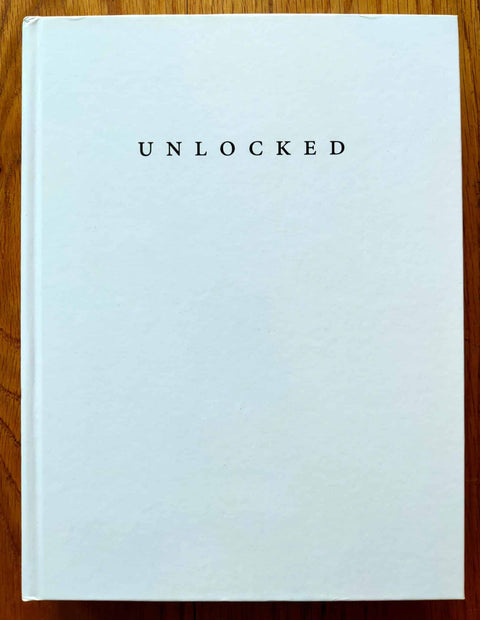 The photography book cover of Unlocked by Vassilis Zidianakis. Hardback in white with capitalised title.