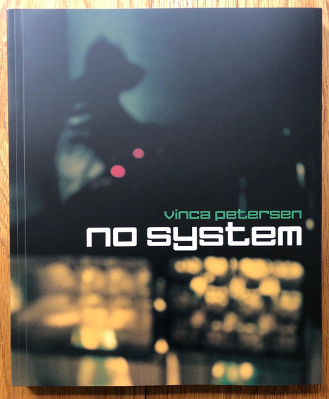 The photography book cover of No System by Vinca Petersen. Paperback with faded image of a DJ at some decks. Signed.
