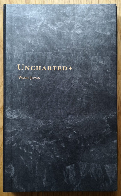 The photography book cover of Uncharted+ by Wang Juyan. Hardback in black and grey. Signed.