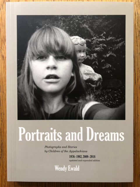 The photography book cover of Portraits and Dreams by Wendy Ewald. Paperback with b&w photo of a child looking into the camera.
