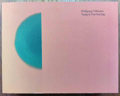 The photography book cover of Today is the First Day by Wolfgang Tillmans. Paperback in light pink/orange with a blue semi circle. Signed.
