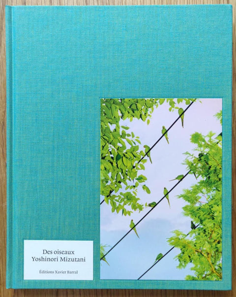 The photography book cover of Des Oiseaux by Yoshinori Mizutani. Hardback in turquoise, image of green birds sitting on a wire.