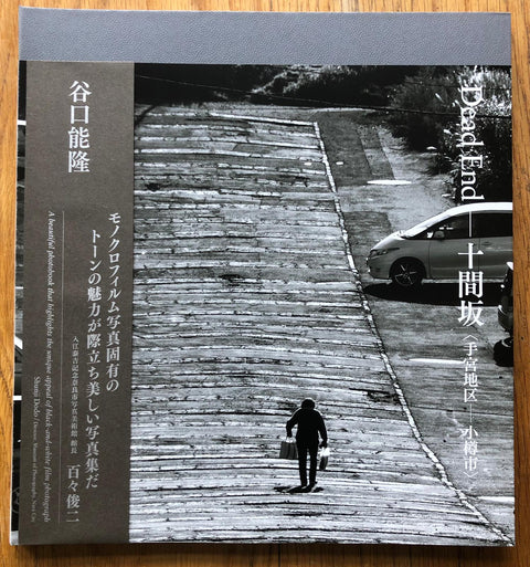 The photography book cover of Dead End: Jukkenzaka (Temiya/Otaru-city) by Yoshitaka Taniguchi. Paperback with B&W image of someone walking up a hill.