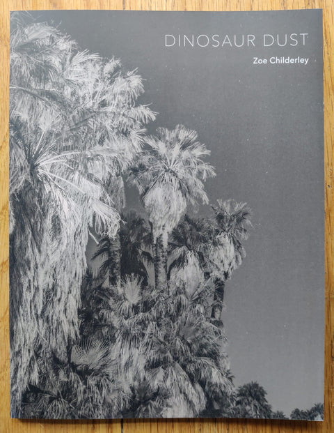 The photography book cover of Dinosaur Dust by Zoe Childerley. Paperback with B&W palm trees on the cover.